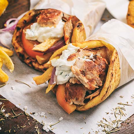 Greek gyros wraped in a pita bread on a wooden background
